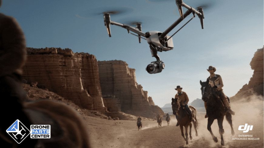 Drohne fliegt über Cowboys in der ockerfarbenen Wüste.