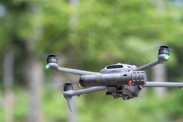 Drone volant en extérieur, forêt en arrière-plan.