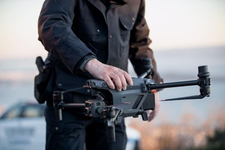 Un opérateur tenant un drone avec une main, prêt à le faire décoller dans un environnement extérieur.