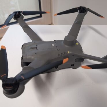 Grey drone on a white table, near the window.