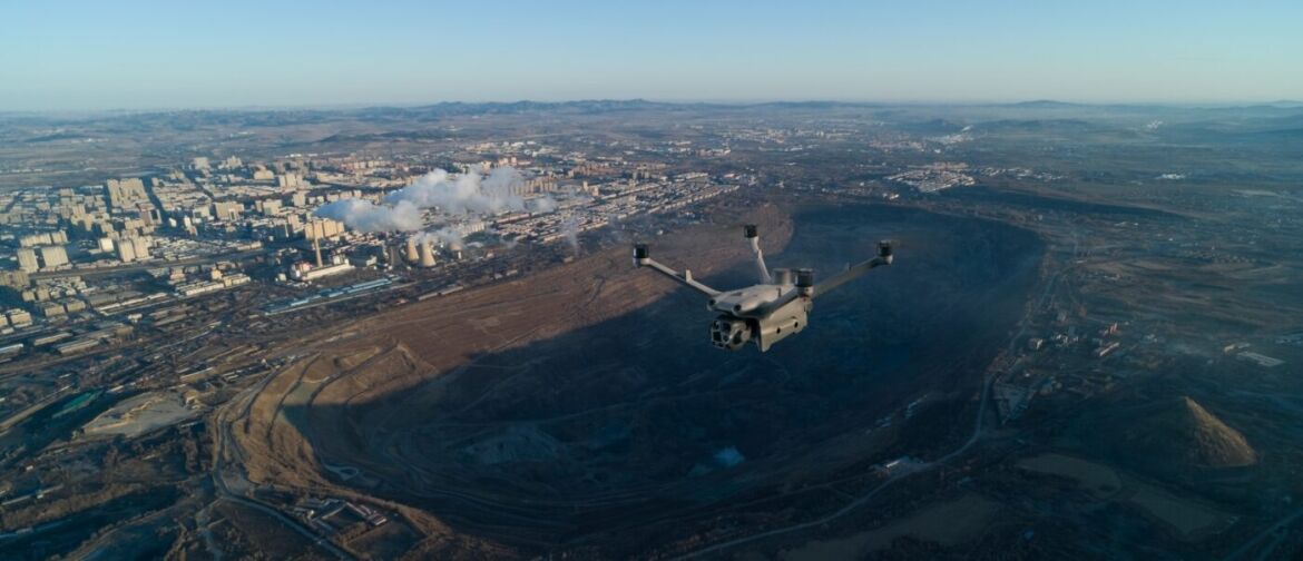 Drone flying over an industrial city at dusk.